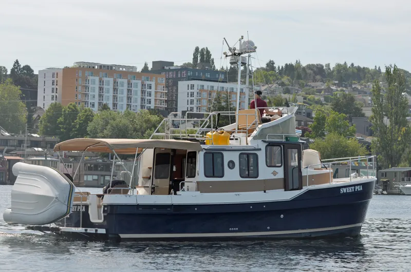 The Image of 2013 Ranger Tugs R-31 CB boat on water, urban backdrop, person on deck. - 0