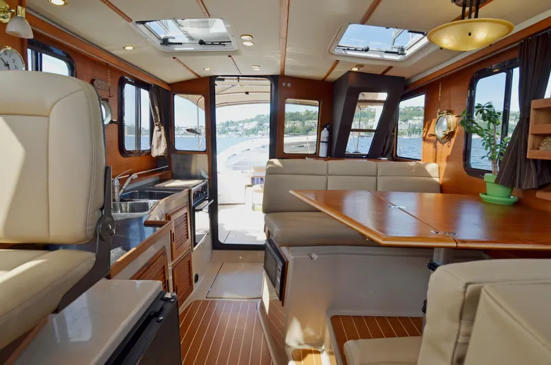 Slide: The Image of Interior of 2013 Ranger Tugs R-31 CB, featuring dining area, kitchenette, and scenic windows. - 21