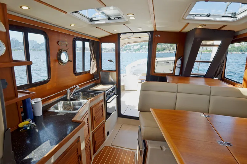 Slide: The Image of Interior of 2013 Ranger Tugs R-31 CB, featuring kitchen and dining area with lake view. - 24
