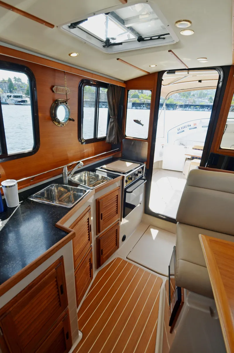 Slide: The Image of Interior of 2013 Ranger Tugs R-31 CB, featuring a compact kitchen and seating area. - 25