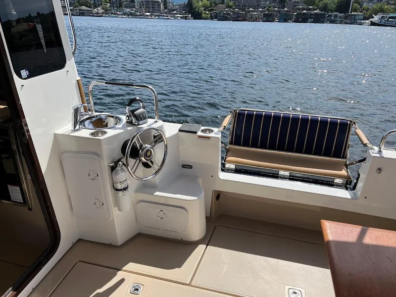 Slide: The Image of 2013 Ranger Tugs R-31 CB boat interior with steering wheel and seating by the water. - 5