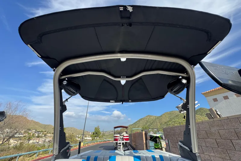 Slide: The Image of 2023 Malibu Wakesetter 21 LX boat with canopy, scenic mountain backdrop. - 16