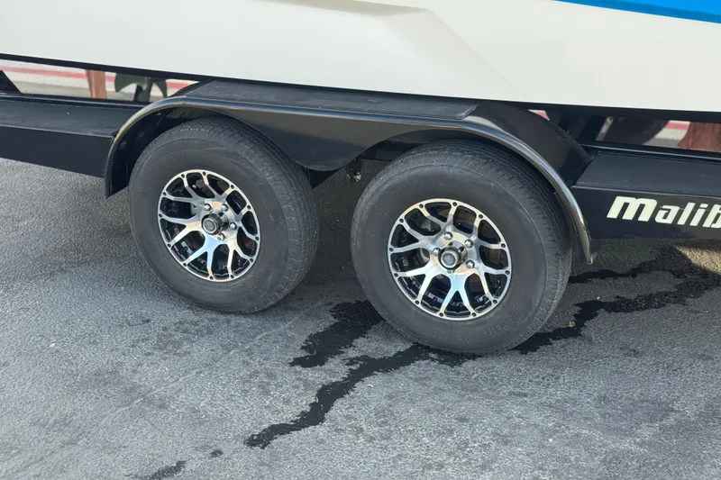 Slide: The Image of 2023 Malibu Wakesetter 21 LX trailer wheels on pavement, showcasing stylish rims. - 38