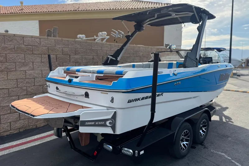 Slide: The Image of 2023 Malibu Wakesetter 21 LX boat on trailer, blue and white design, parked outdoors. - 5