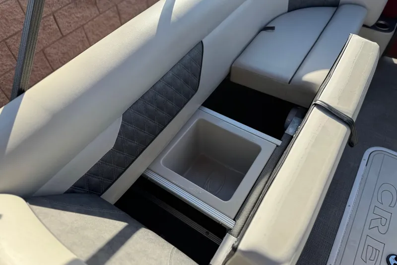 Slide: The Image of 2021 Crest Classic DLX 240 SLC boat interior with storage compartment and cushioned seating. - 15