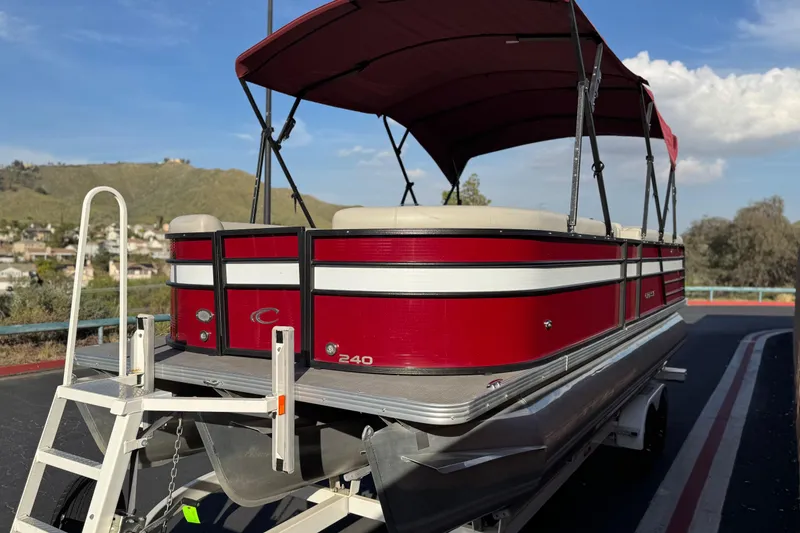 Slide: The Image of 2021 Crest Classic DLX 240 SLC pontoon boat with red and white exterior on trailer. - 3