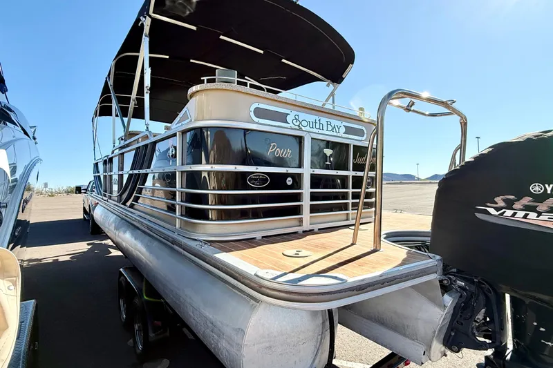 Slide: The Image of 2014 South Bay 724 E DLX TT pontoon boat with canopy, parked outdoors. - 2