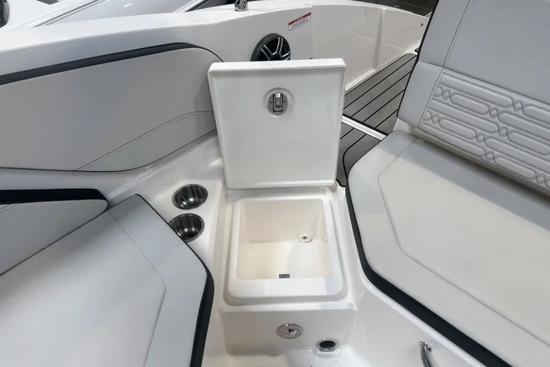 Slide: The Image of 2026 Sea Ray SPX 210 Outboard interior with open storage compartment and cup holders. - 16