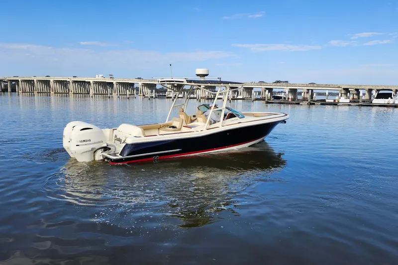 Slide: The Image of 2016 Chris-Craft Calypso 26 boat on calm water near a bridge, featuring Yamaha engines. - 12