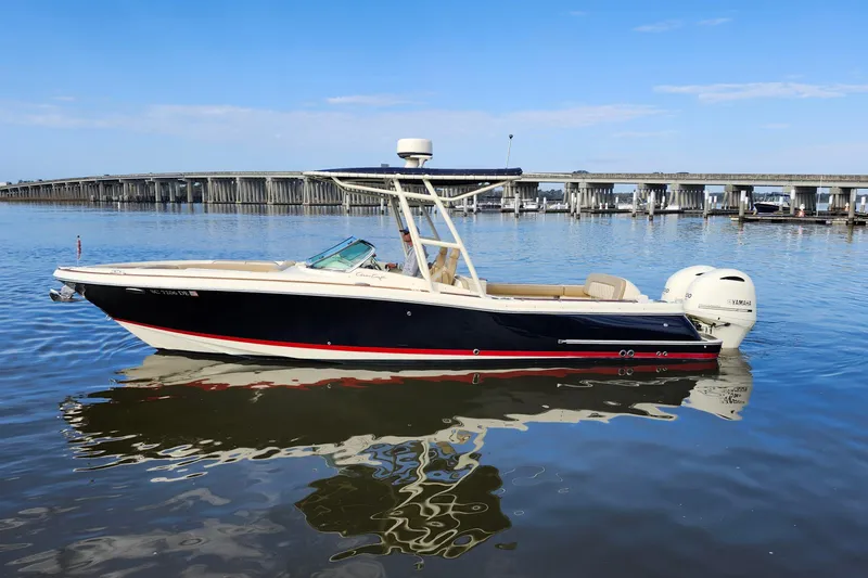 Slide: The Image of 2016 Chris-Craft Calypso 26 boat on calm water with bridge in background. - 2