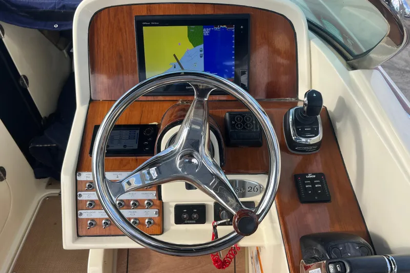 Slide: The Image of 2016 Chris-Craft Calypso 26 boat dashboard with steering wheel and navigation controls. - 24