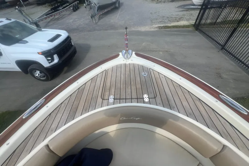 Slide: The Image of 2016 Chris-Craft Calypso 26 boat with wooden deck, parked near a white truck. - 36