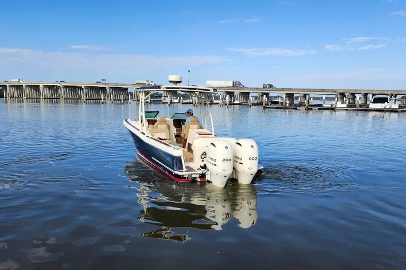 Slide: The Image of 2016 Chris-Craft Calypso 26 boat with twin Yamaha engines on calm water near a bridge. - 8