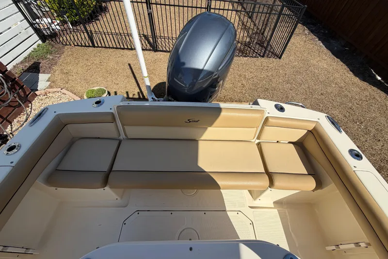 Slide: The Image of 2017 Scout 225 XSF boat with beige seating and outboard motor in a yard. - 13