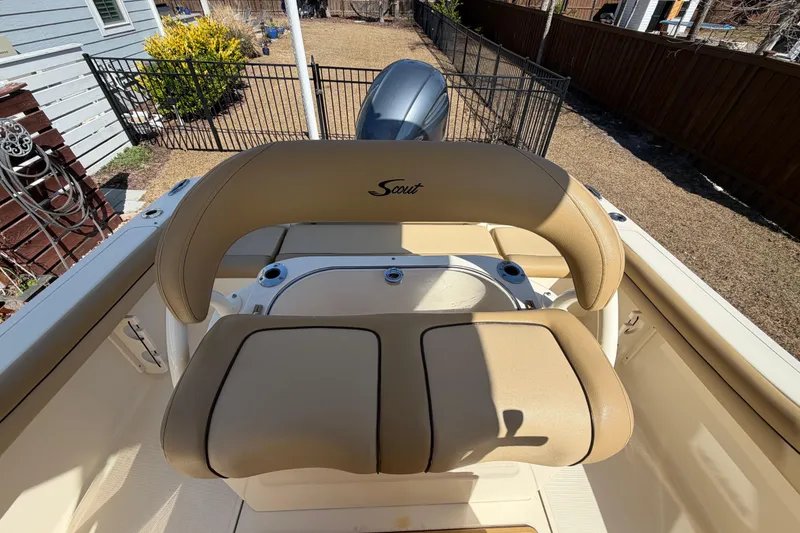 Slide: The Image of 2017 Scout 225 XSF boat interior with tan seating and console, parked outdoors. - 15