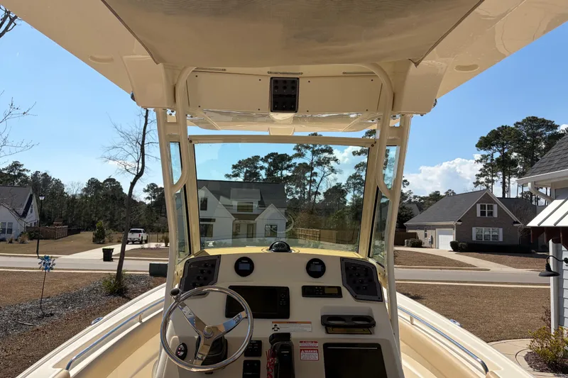 Slide: The Image of 2017 Scout 225 XSF boat dashboard with steering wheel, parked in suburban neighborhood. - 17