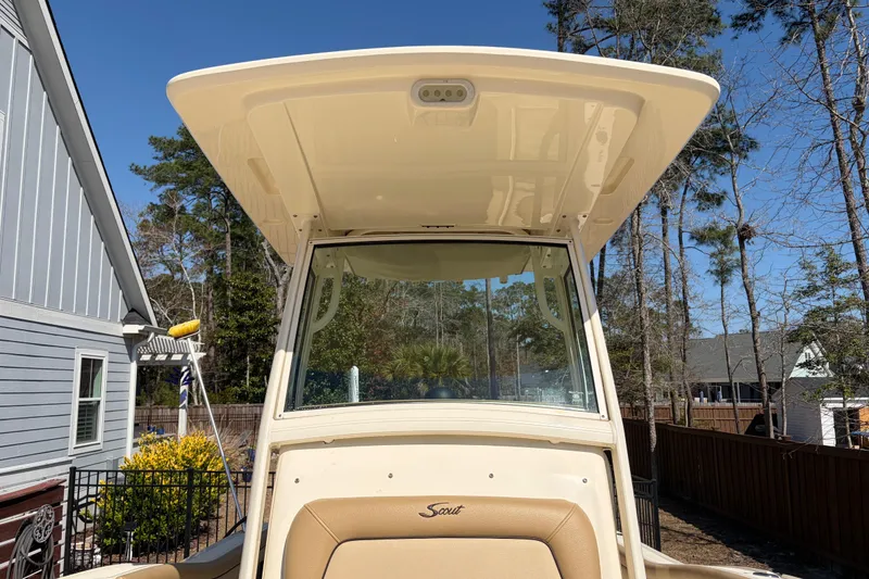 Slide: The Image of 2017 Scout 225 XSF boat with T-top, parked outdoors near trees and houses. - 23