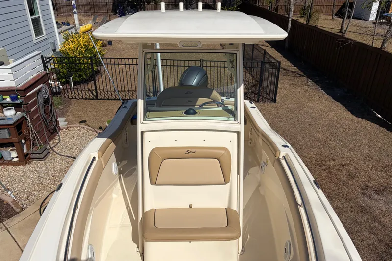 Slide: The Image of 2017 Scout 225 XSF boat with beige seating and helm, parked in a backyard. - 24