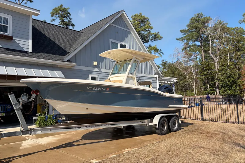 Slide: The Image of 2017 Scout 225 XSF boat on trailer in driveway, near house and trees. - 8