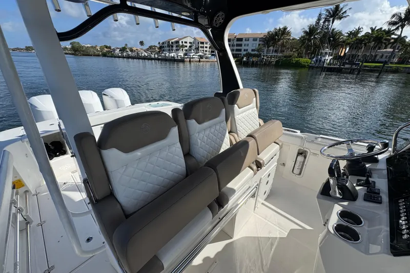 Slide: The Image of 2017 Edgewater 368CC boat interior with luxurious seating and steering console by the water. - 17