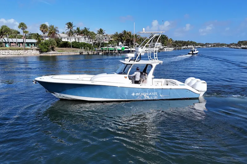 Slide: The Image of 2017 Edgewater 368CC boat cruising on a sunny day near palm-lined shore. - 6
