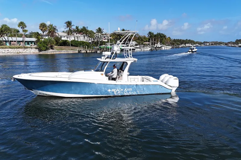 Slide: The Image of 2017 Edgewater 368CC boat cruising on a sunny day near palm-lined shore. - 7