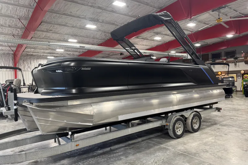 The Image of 2025 Manitou 24 Explore pontoon boat on trailer in indoor showroom. - 1
