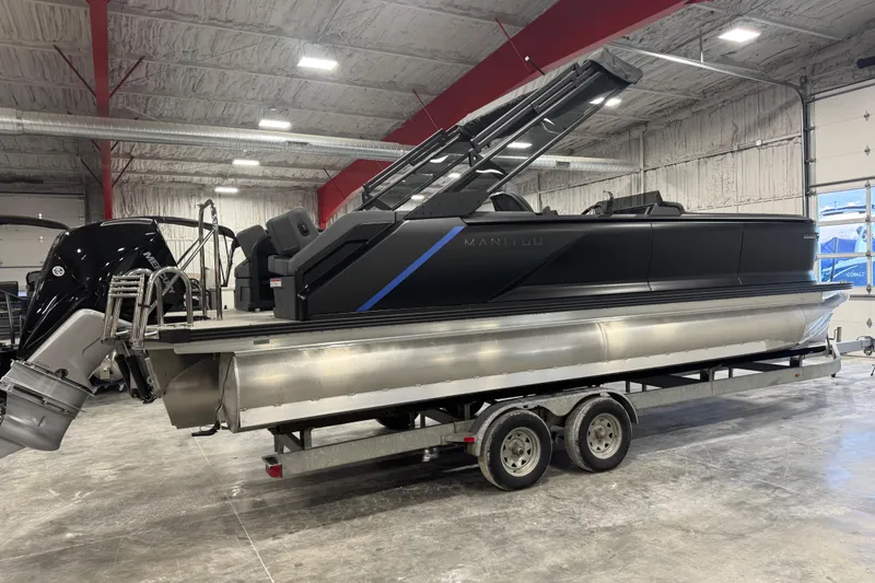 Slide: The Image of 2025 Manitou 24 Explore pontoon boat on trailer in indoor showroom. - 4