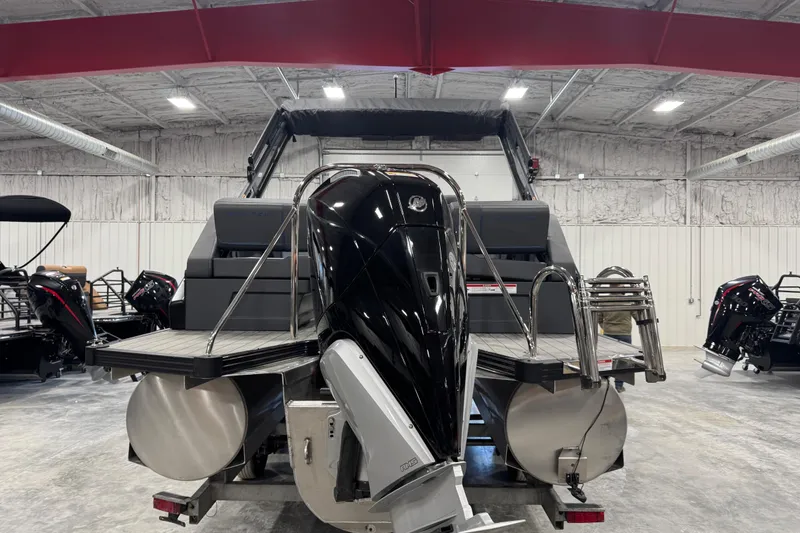Slide: The Image of 2025 Manitou 24 Explore pontoon boat in showroom, rear view with outboard motor. - 6