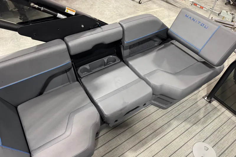 Slide: The Image of 2025 Manitou 24 Explorer boat seating with gray upholstery and blue accents. - 13