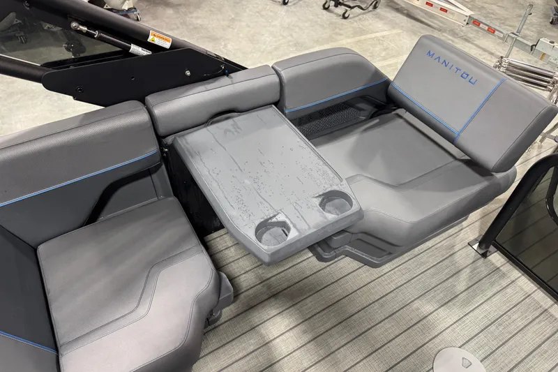 Slide: The Image of 2025 Manitou 24 Explorer boat interior with gray seating and integrated table. - 14