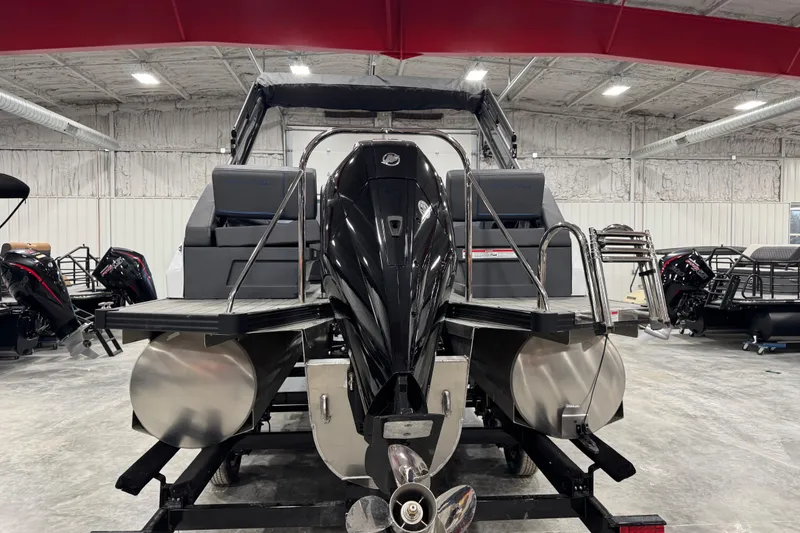 Slide: The Image of 2025 Manitou 24 Explorer pontoon boat in a showroom, rear view with motor and ladder. - 6