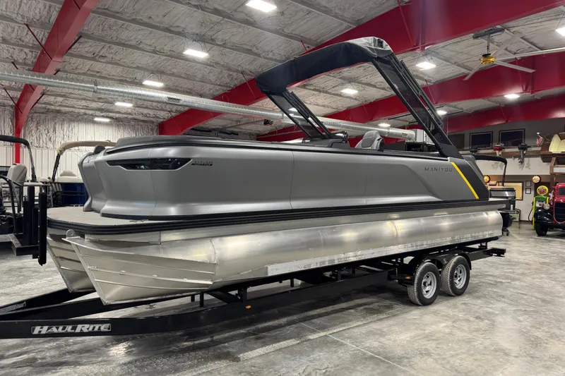 The Image of 2024 Manitou 24 Explorer pontoon boat on trailer in indoor showroom. - 0