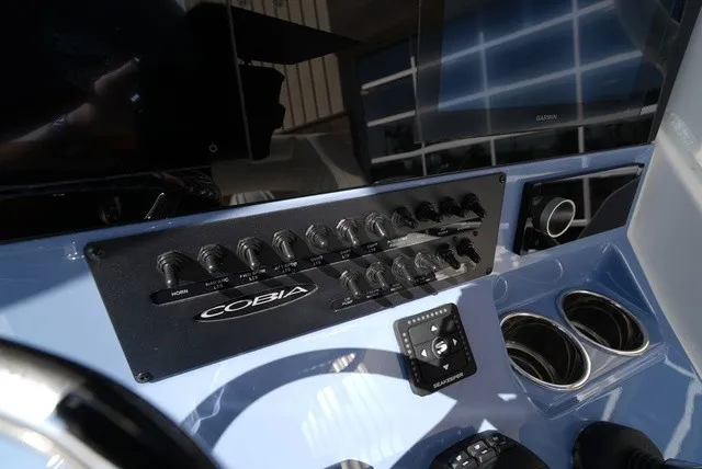Slide: The Image of Dashboard of a Cobia 245 Center Console boat with switches and cup holders. - 24