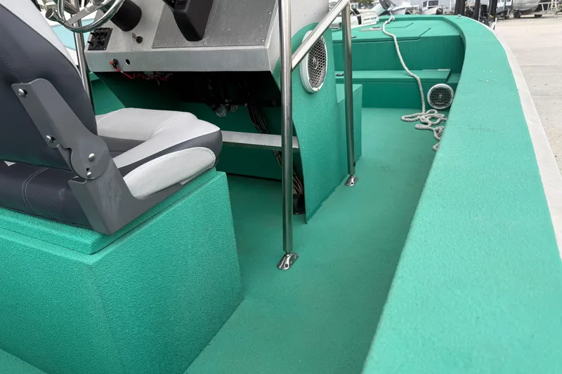 Slide: The Image of Interior of a 2012 Charles Leonard model 24 boat with green flooring and seating. - 13