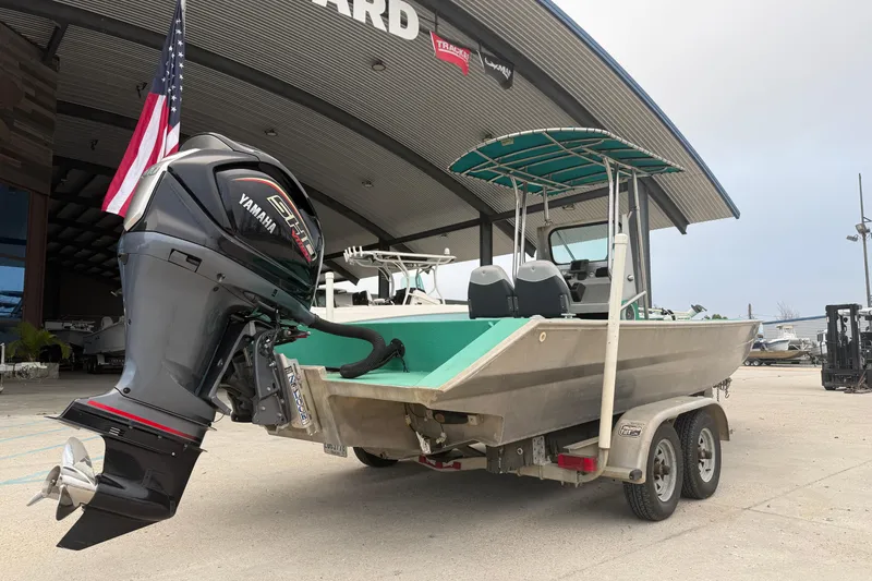 Slide: The Image of Boat with Yamaha engine on trailer, Charles Leonard 24 model, 2012, parked near a building. - 2