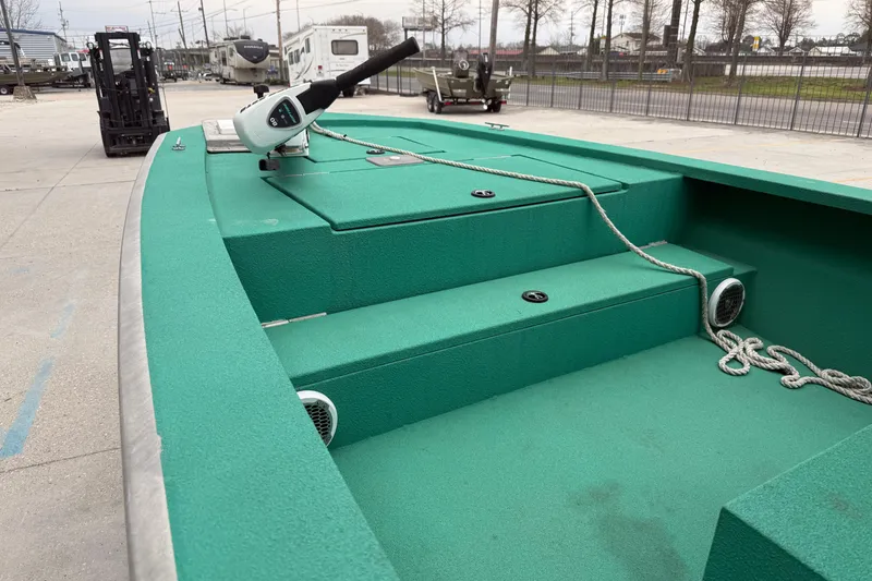 Slide: The Image of Green Charles Leonard 24 boat deck with rope and motor, parked in an outdoor lot. - 6
