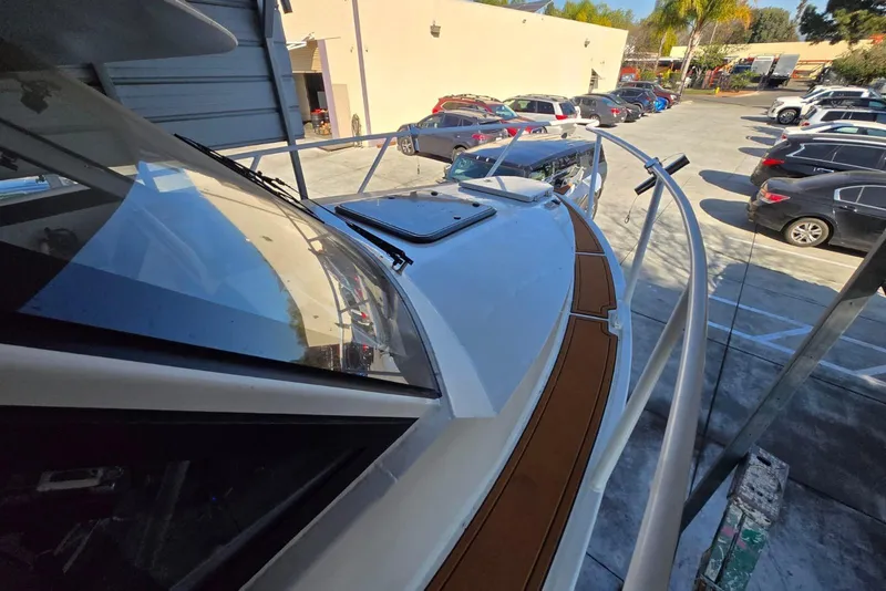 Slide: The Image of Custom Boat 34, 2025 model, docked in a parking lot with surrounding vehicles. - 8
