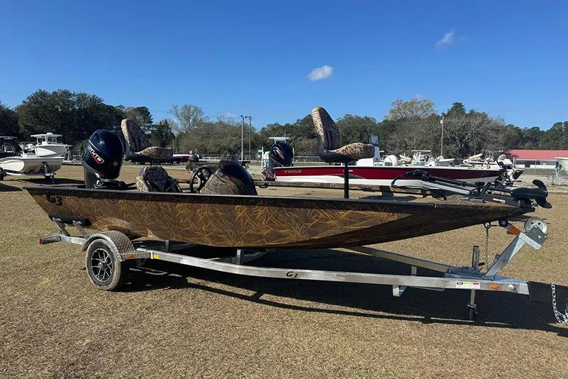 The Image of 2026 G3 Sportsman 1710 boat on trailer, camo design, parked outdoors. - 1