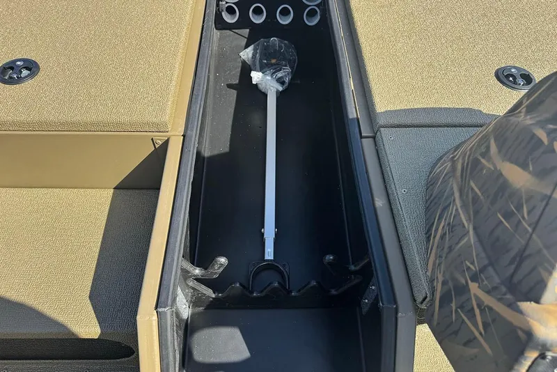Slide: The Image of 2026 G3 Sportsman 1710 boat storage compartment with rod holders and beige interior. - 14