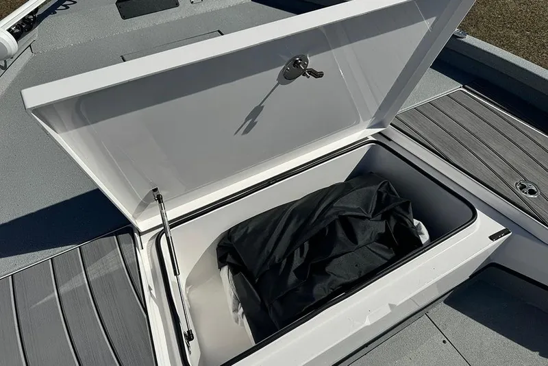 Slide: The Image of Open storage compartment on 2026 Vexus ACX 2210 boat, featuring secure lock and black cover. - 16