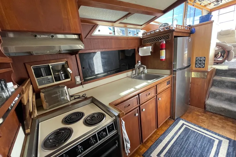 Slide: The Image of 1975 Uniflite Sport Fisher 42 kitchen with stove, sink, and refrigerator in wooden interior. - 14