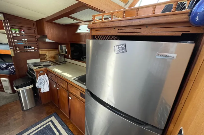 Slide: The Image of 1975 Uniflite Sport Fisher 42 yacht kitchen with Frigidaire fridge and wooden cabinetry. - 16