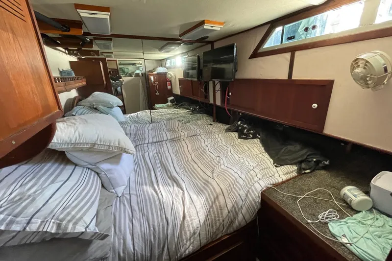 Slide: The Image of 1975 Uniflite Sport Fisher 42 cabin interior with bed, pillows, and wooden storage. - 18