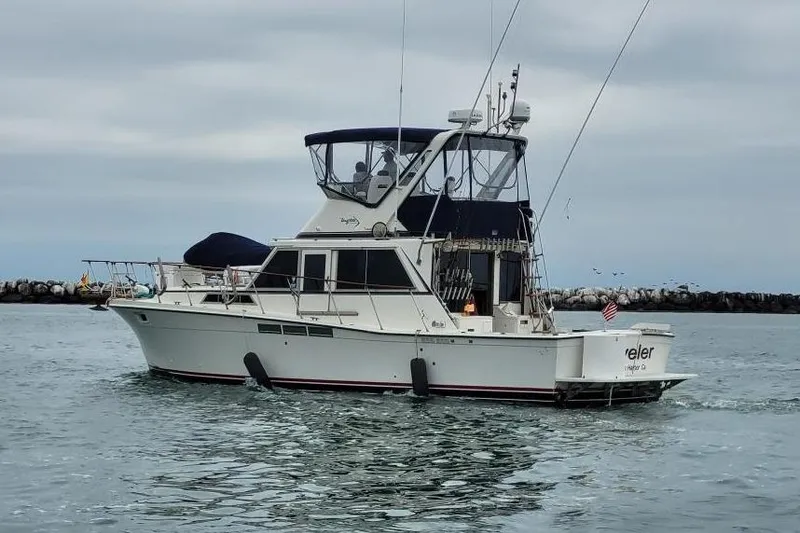 Slide: The Image of 1975 Uniflite Sport Fisher 42 boat on water, overcast sky, American flag displayed. - 26