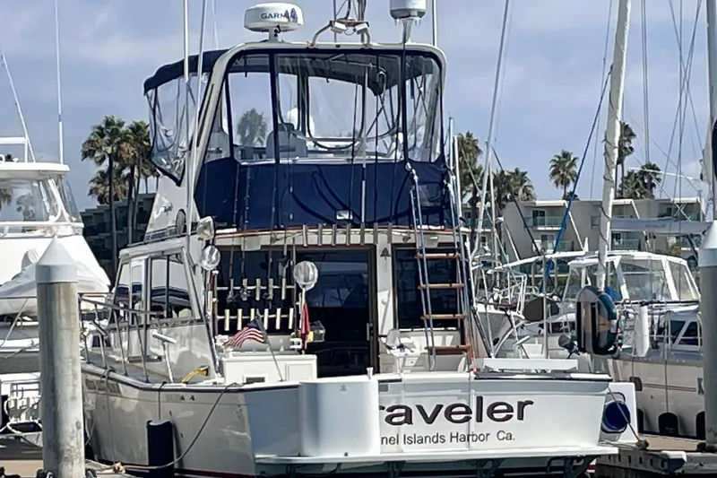 Slide: The Image of 1975 Uniflite Sport Fisher 42 docked at marina, featuring blue canopy and fishing equipment. - 28