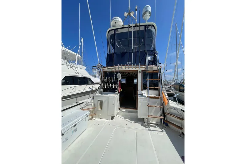 Slide: The Image of 1975 Uniflite Sport Fisher 42 yacht docked, featuring fishing rods and equipment under a clear blue sky. - 5