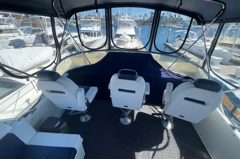 Slide: The Image of 1975 Uniflite Sport Fisher 42 cockpit with three white captain chairs, marina view. - 7