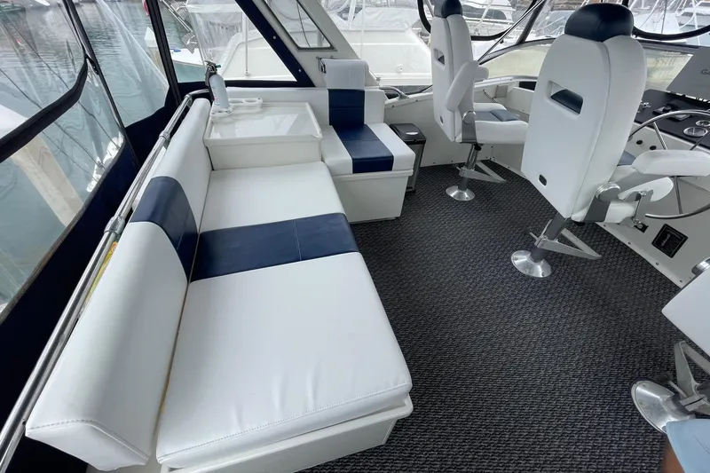Slide: The Image of 1975 Uniflite Sport Fisher 42 interior with white and navy seating, helm chairs, and carpeted floor. - 8
