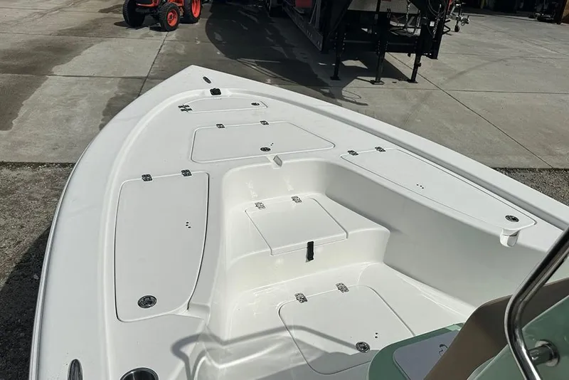 Slide: The Image of 2026 Sea Pro 230 Bay boat deck with storage compartments, parked on concrete. - 10